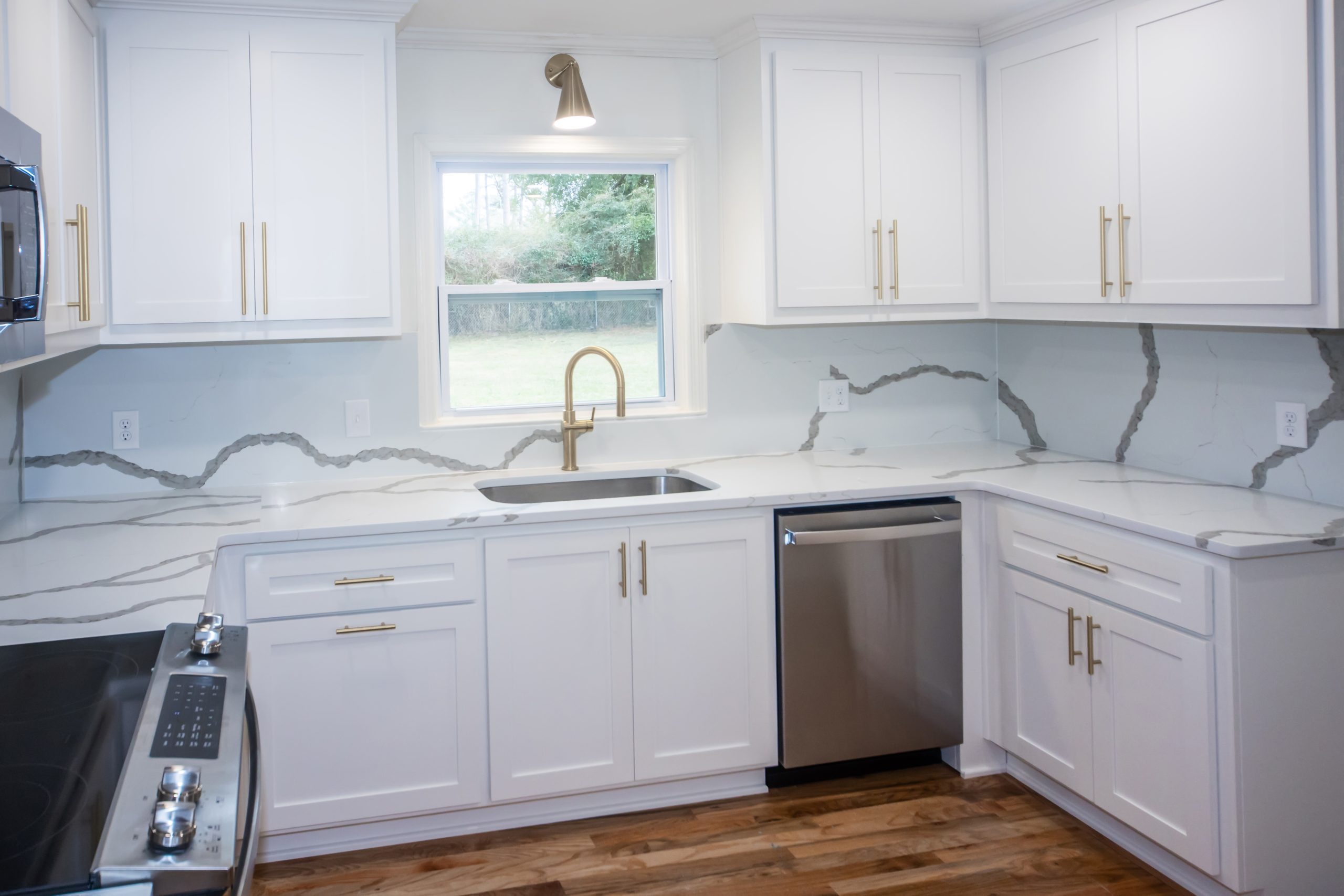 Newly remodeled white shaker kitchen with quartz island and gold hardware in a North Shore home