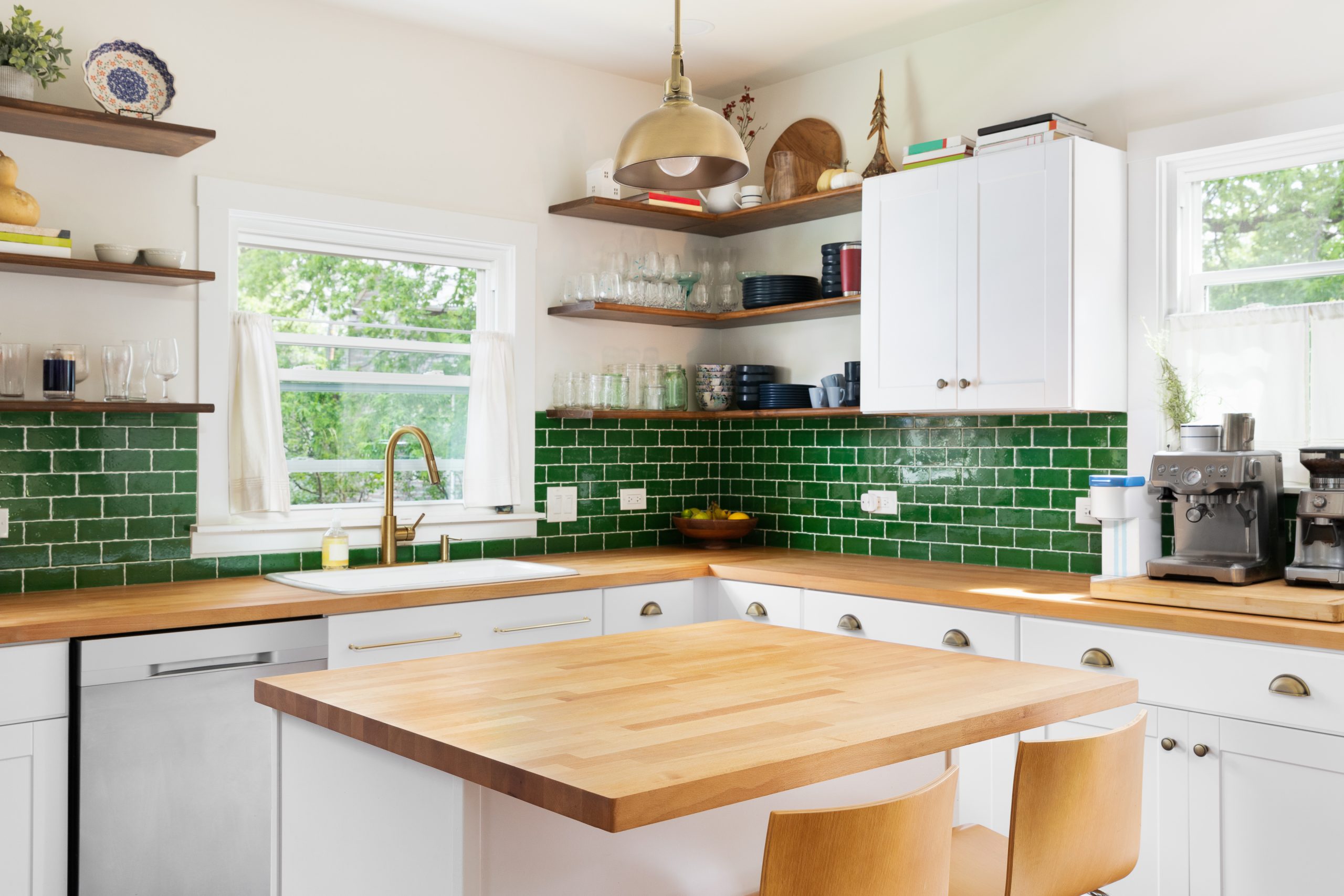 Walnut butcher block kitchen island with white shaker cabinets, brass pendant, and green subway tile backsplash in a refined North Shore kitchen