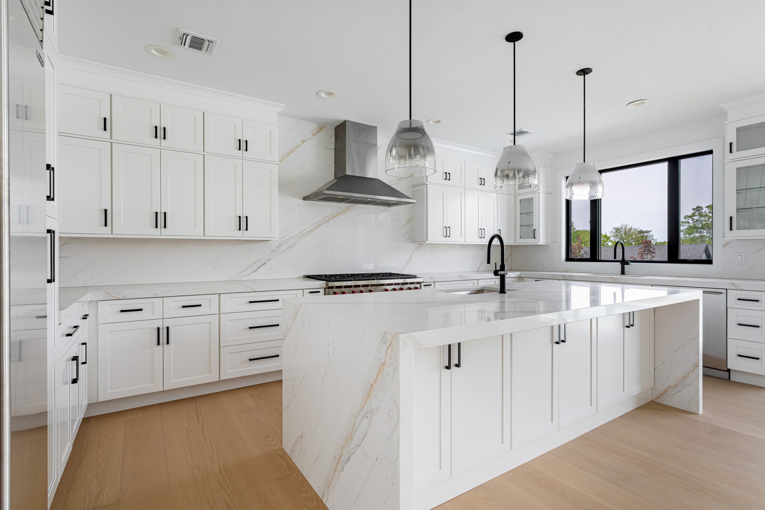 Bright modern North Shore kitchen with a large veined white quartzite island and pendant lighting in a minimalist contemporary design